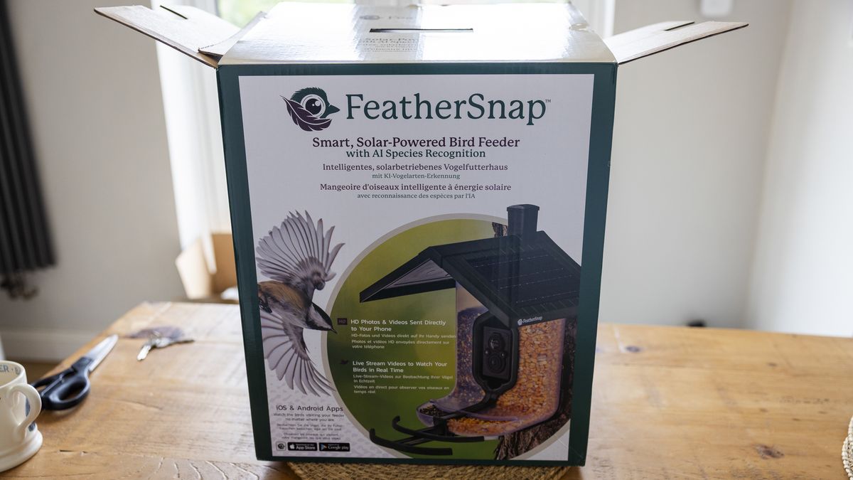 The FeatherSnap Scout bird feeder being unboxed on a wooden dining table