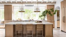 A white oak kitchen with marble countertops and brass accents