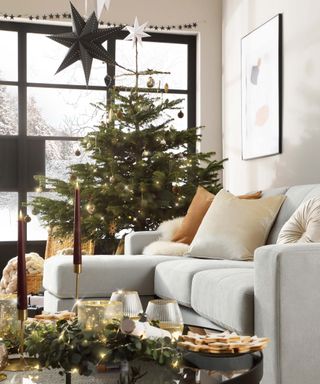 christmas tree in living room by a beige sofa with cushions