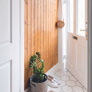 Hallway with floor to ceiling wood panelling and white hexagonal tile flooring.