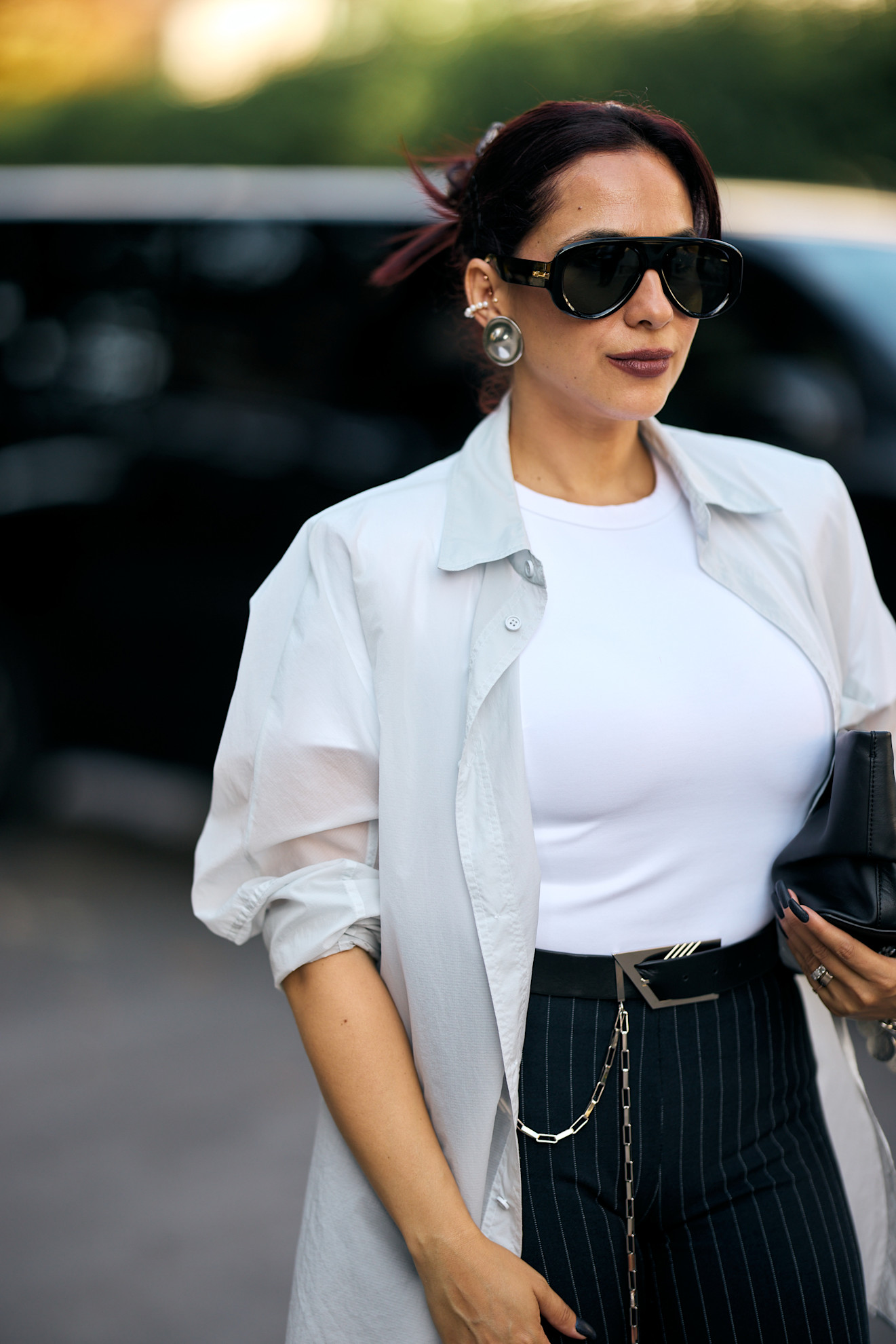 a white woman in a white t shirt and sheer shirt with dark lipstick and deep purple hair