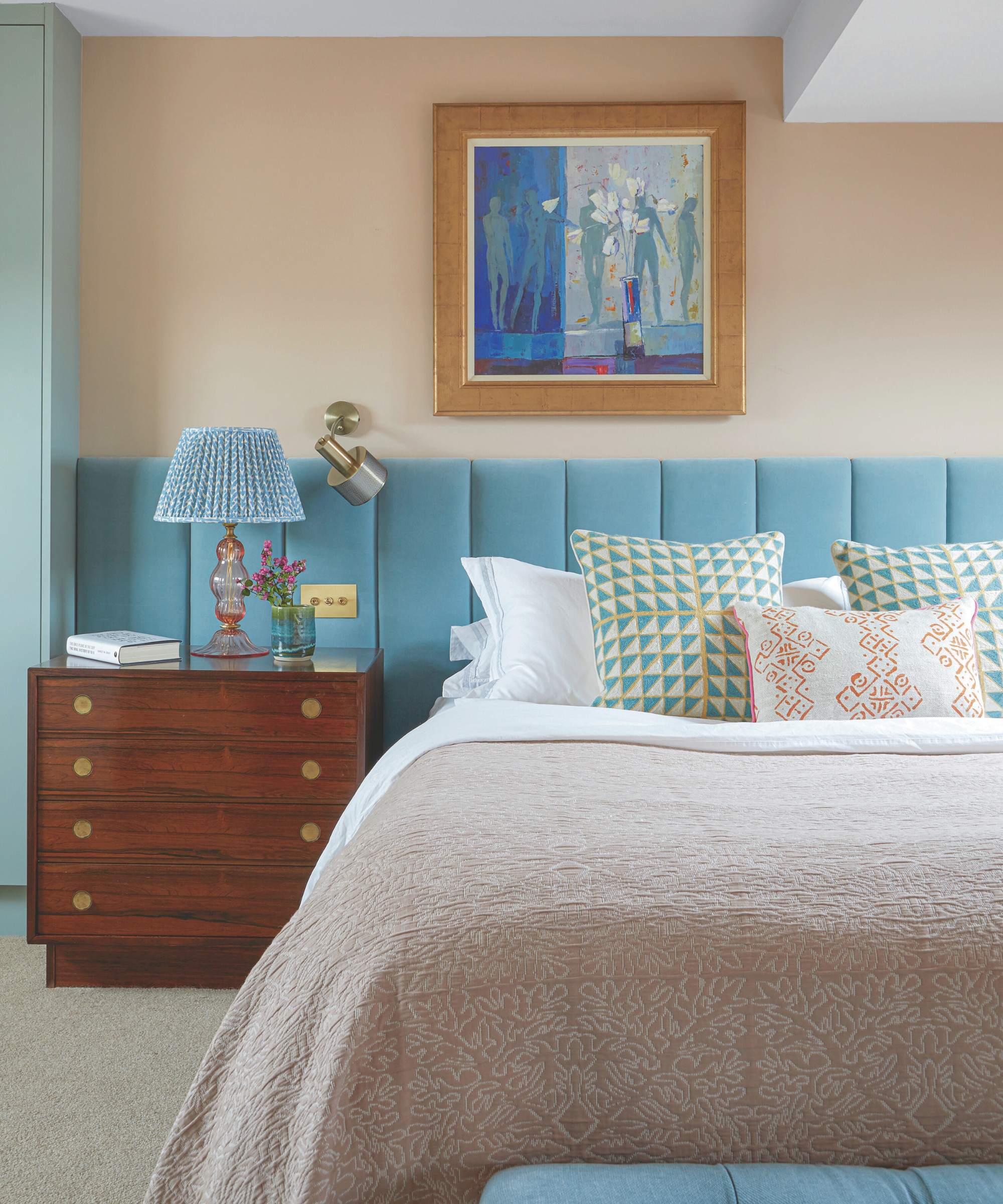 a bedroom with a large bed with pillows, a light blue headboard, and a wood side table