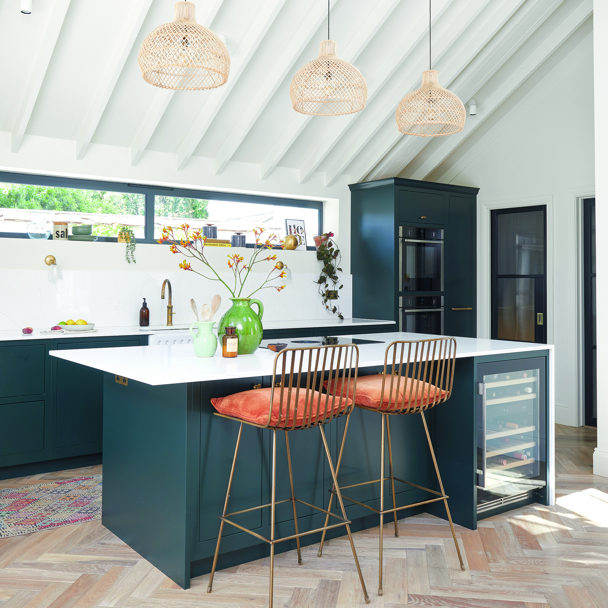 Black kitchen with island, wine fridge and rust coloured bar stools