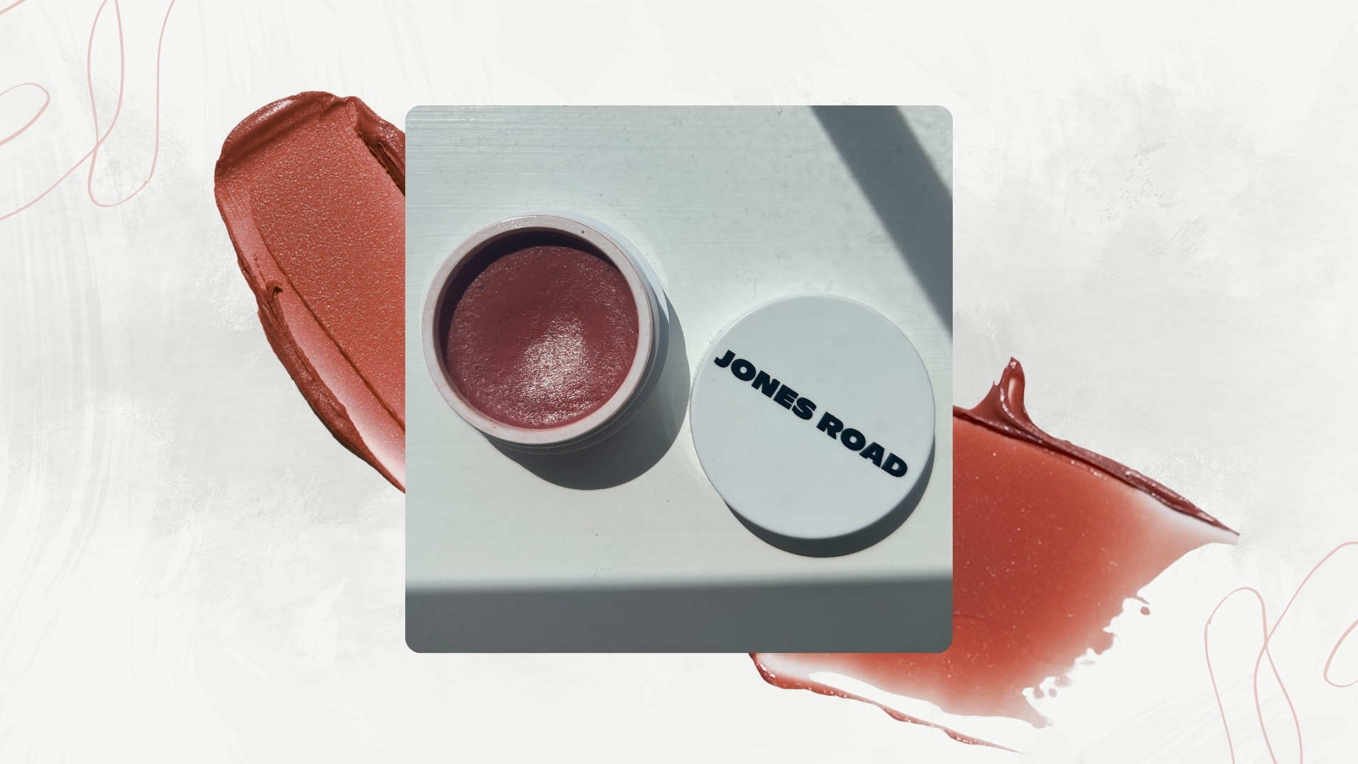 Image of open Jones Road Miracle Balm in shade 'Chic' on a white marble background, blush swatches and two swirl details