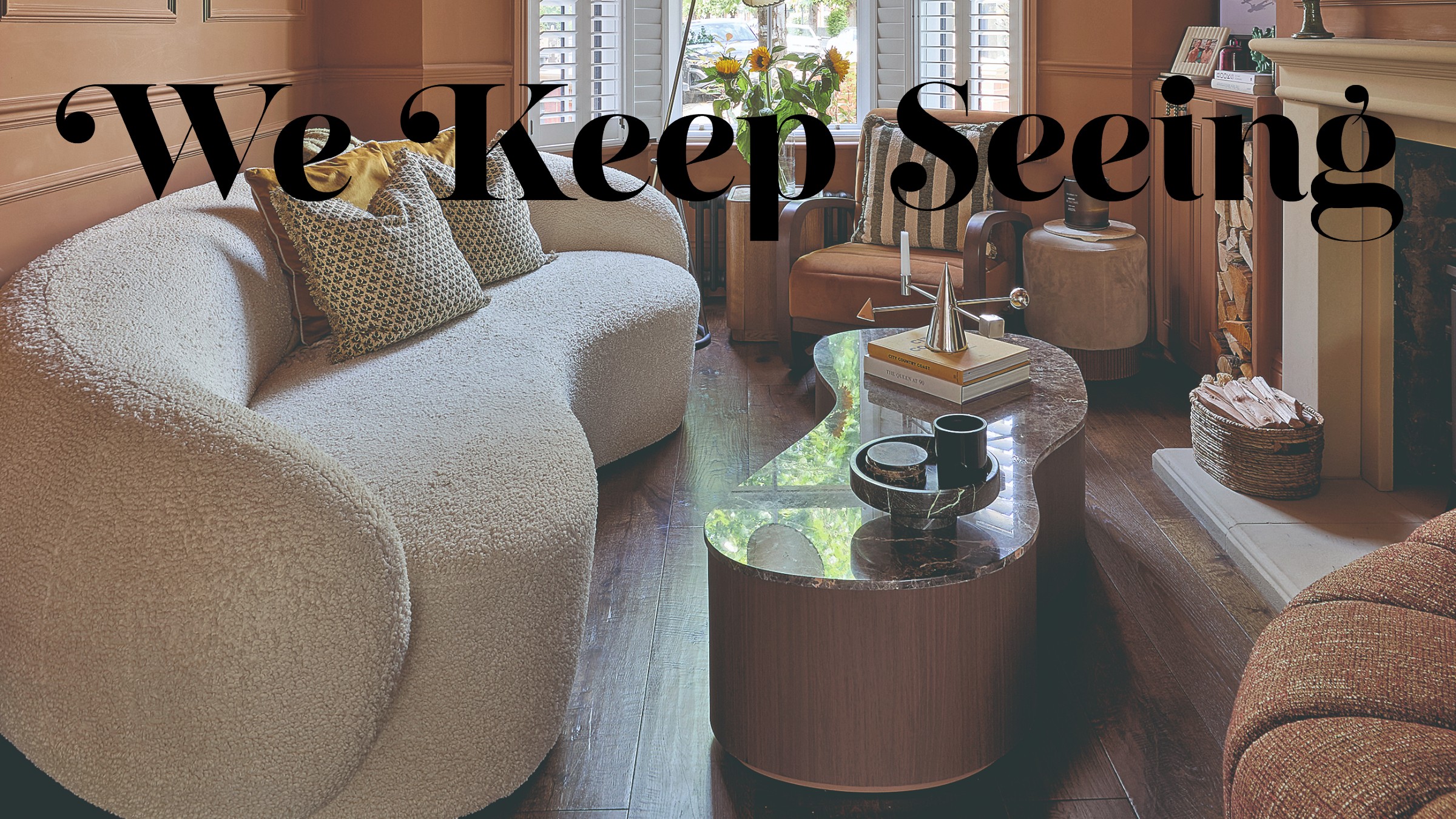 A terracotta-painted living room with an organically shaped marble-top flutted coffee table and a curved white boucle sofa