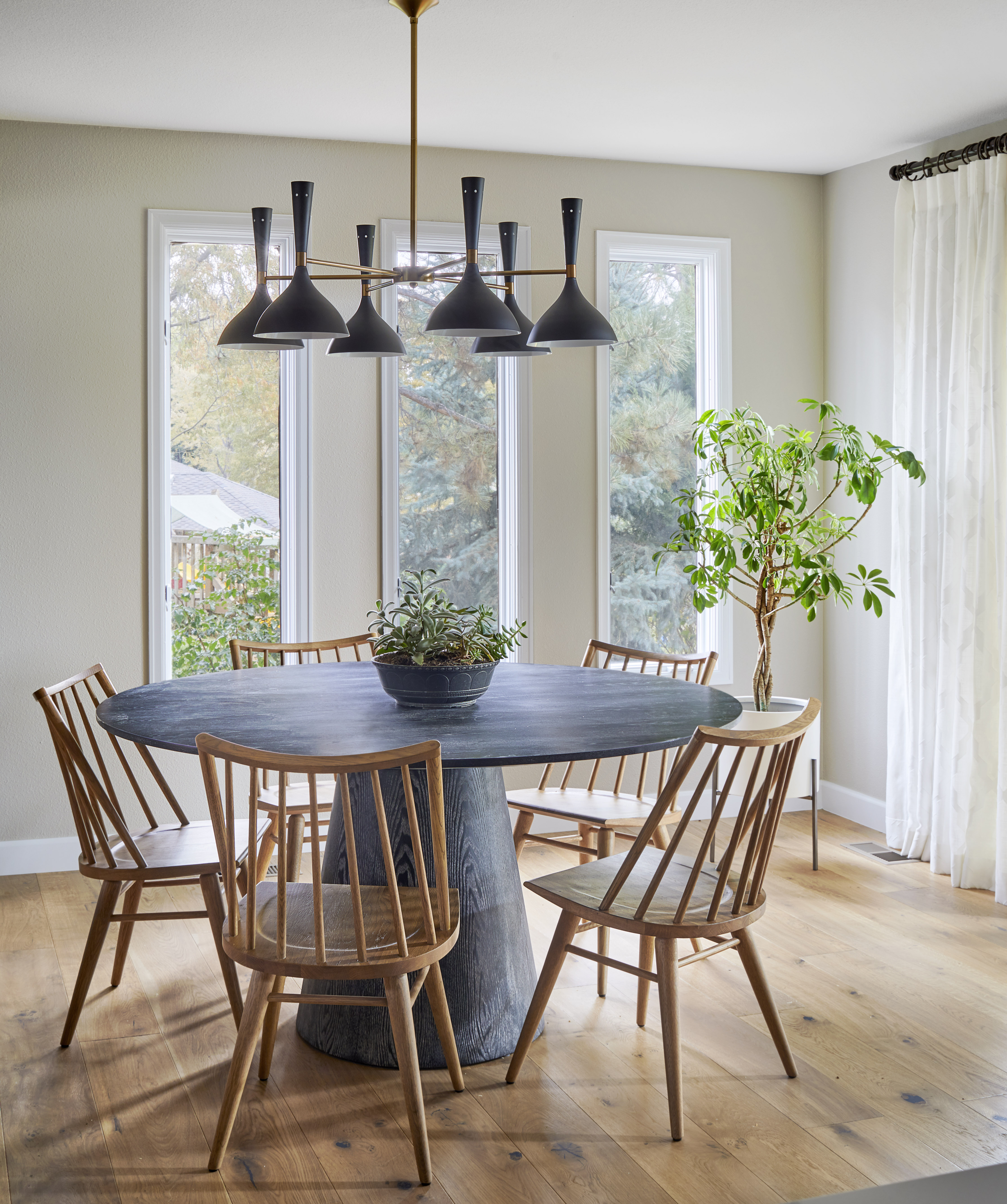 A small dining room with a rond table and wooden chairs placed around it