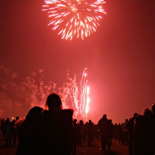 people watching red fireworks