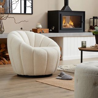 Homebase boucle armchair in a living room with a wood fire, wood floors, and other furniture