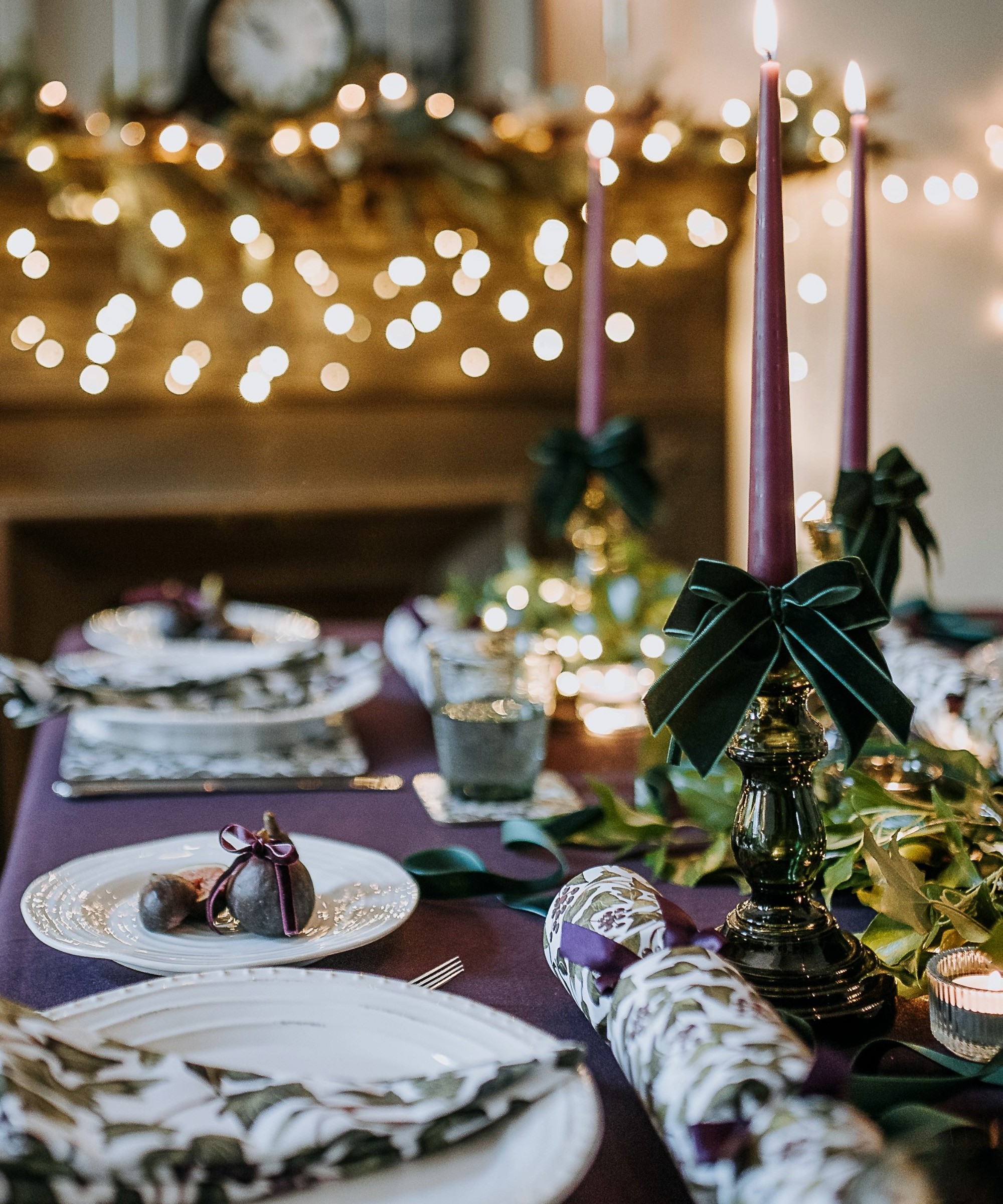 Christmas table with bows on candles and purple tablecloth