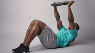 Weight plate crunch reach exercise