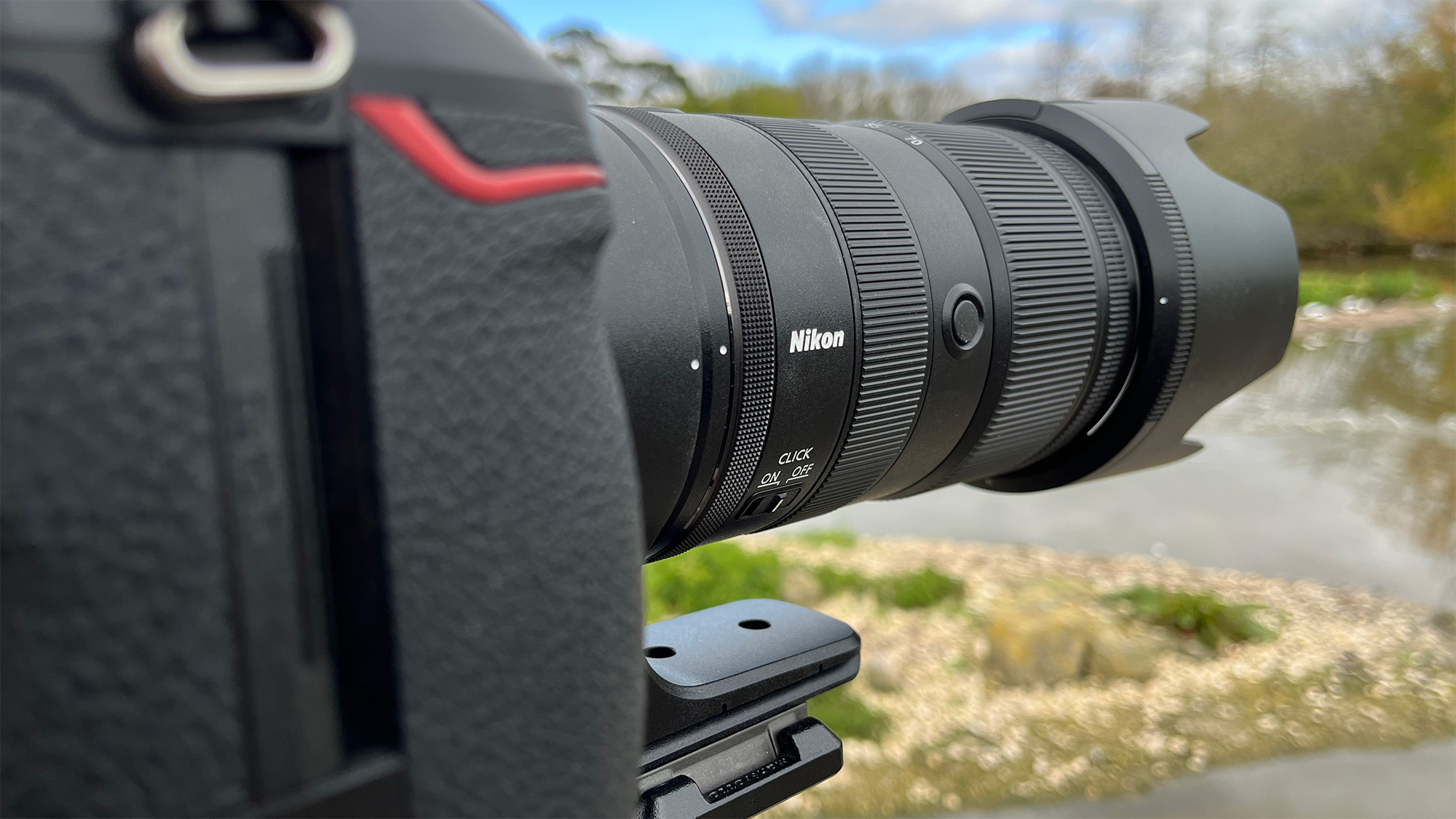 Mike Harris holding Nikon Z 70-200mm f/2.8 VR S II by a lake with vegetation and trees in the background