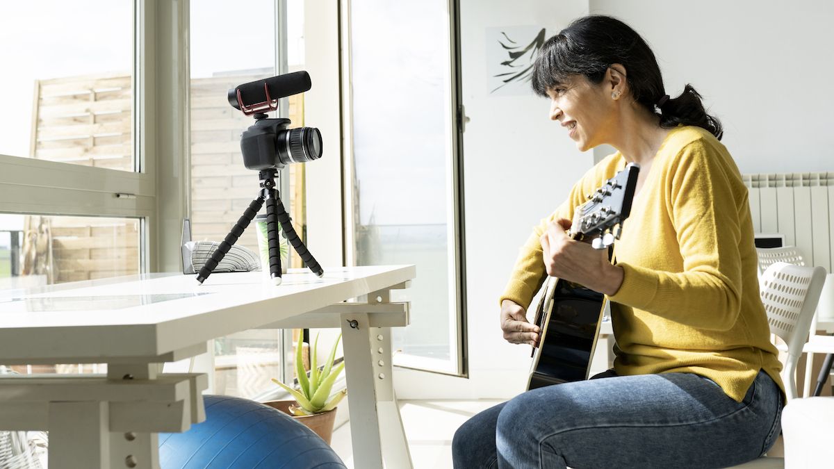 Woman wearing a yellow top record a guitar vlog