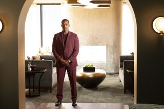 Solos: Tom, played by Anthony Mackie, stands in a burgundy suit in a slick, chrome-filled living room, looking pensive