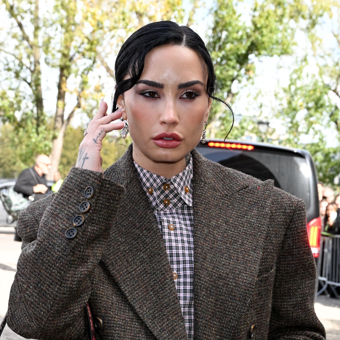 a white woman with black hair pulled into a bun being photographed by paparazzi
