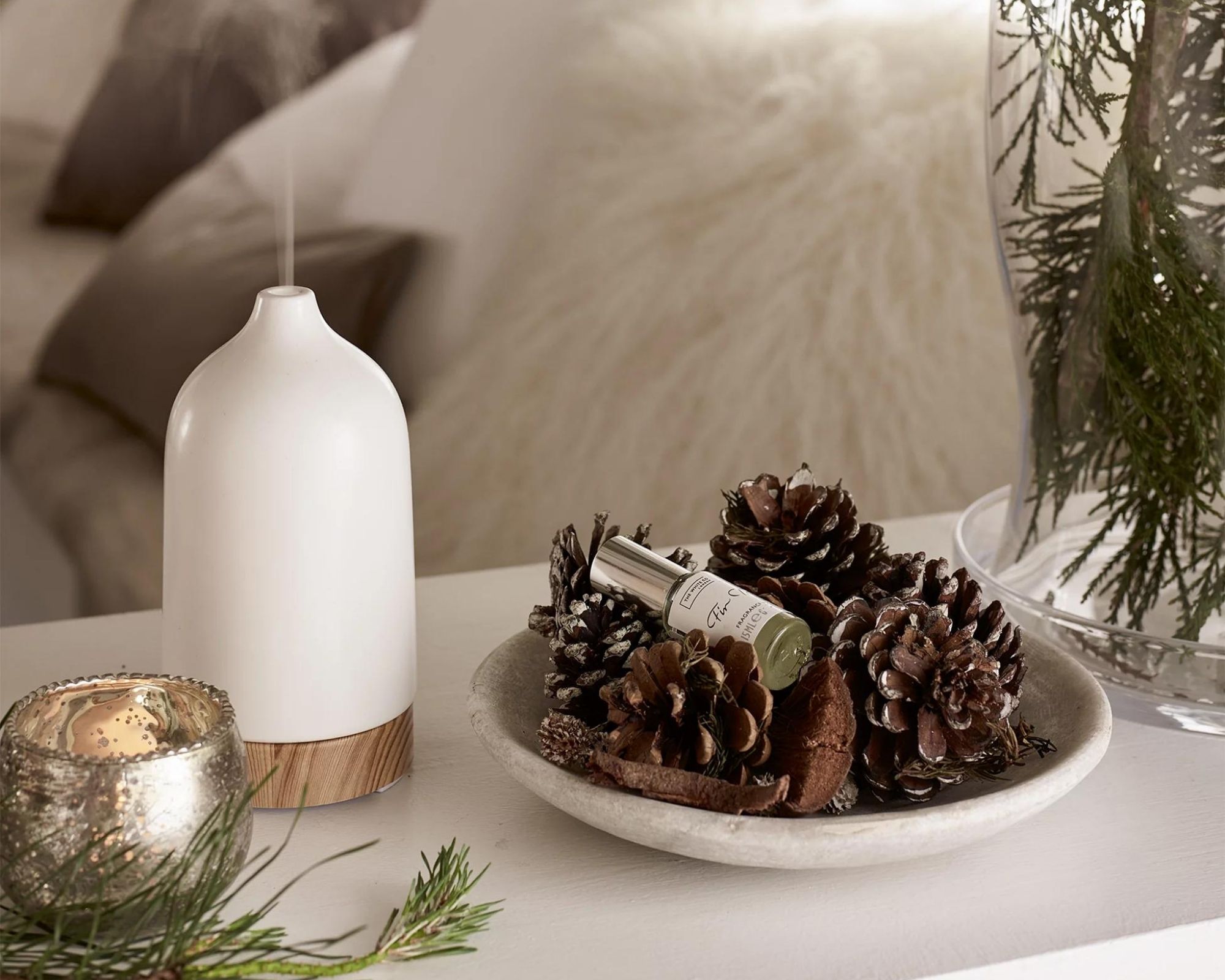 The White Company Electronic Diffuser displayed on side next to a bowl of pinecones