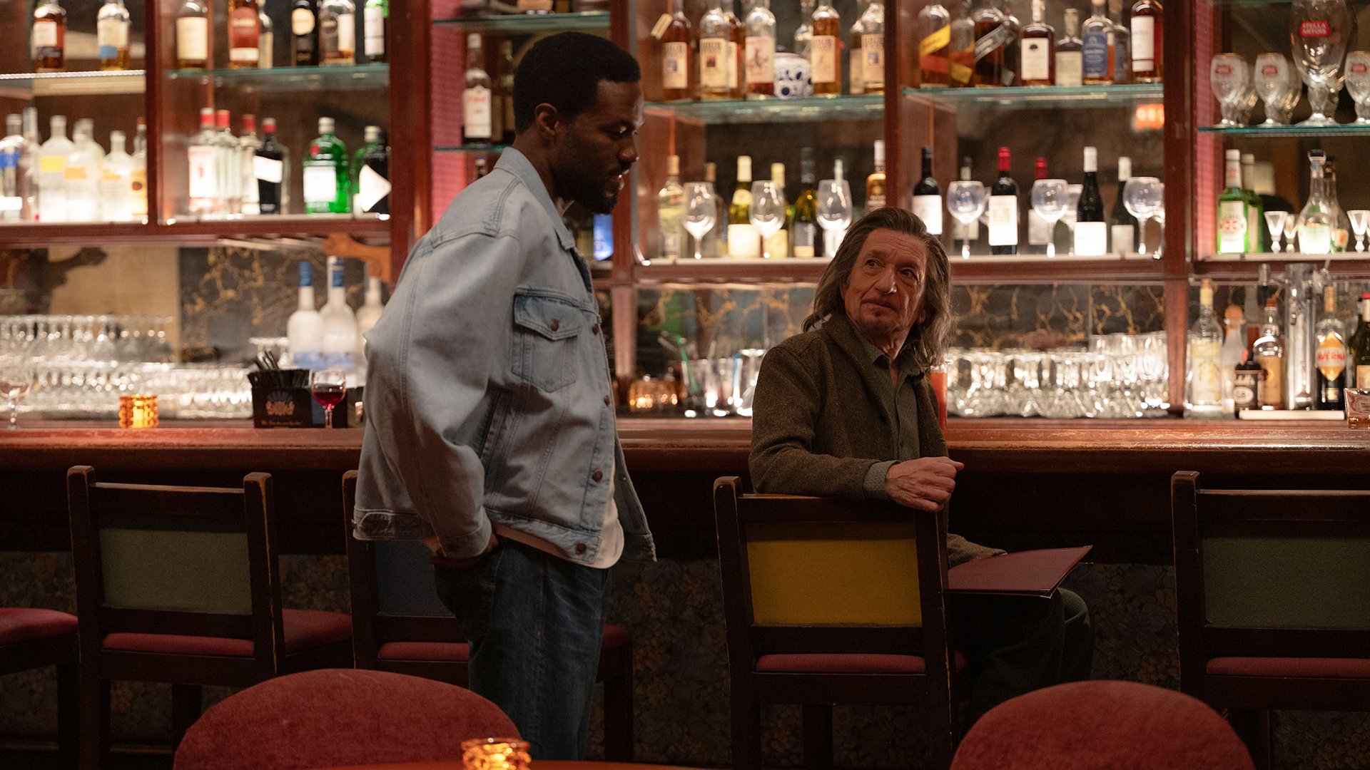 Simon Williams standing with his hands on his hips and looking down as Trevor Slattery sits at a bar in Marvel's Wonder Man