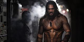 Aquaman walks toward the camera as steam billows behind him