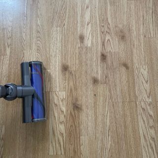 Dyson V12 on wooden floor with clumps of hair on it