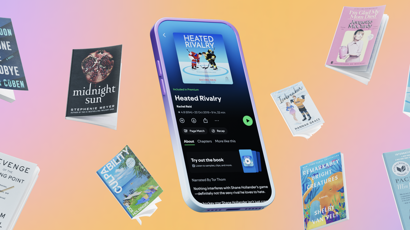 A smartphone with a Spotify audiobook of Heated Rivalry surrounded by physical copies of popular literature 