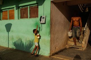 A child reaches for a telephone against a green wall