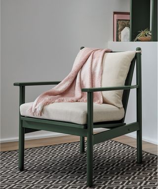 Upcycled chair in deep green shade with soft pink throw, and graphic geo mono floor rug.