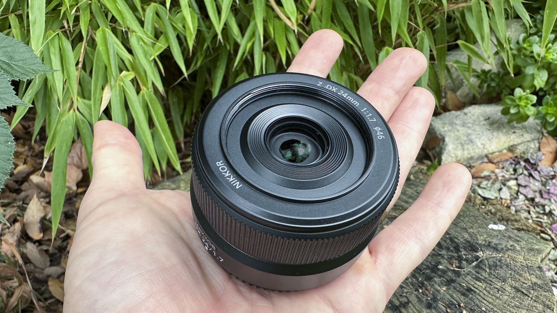 Nikkor Z DX 24mm f/1.7 lens pictured in hand showing how small and light the lens is