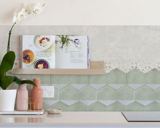 Mint hexagonal wall tiles with orchid plant, and open recipe book on shelf.