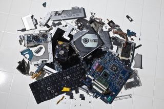 A pile of smashed computer parts pictured on a white tiled floor