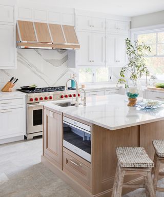 Kitchen with white cabinets and wood island, range, marble backsplash and neutral tile floor