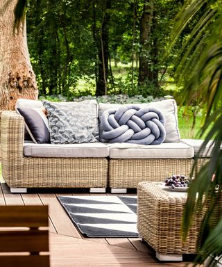 Comfortable rattan couch on a sunny patio of a calm summer house during the weekend