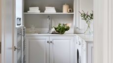 white laundry room with open shelving and cabinetry with sink and washing machine