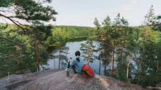 Woman looking at lake in Finland and drinking tea
