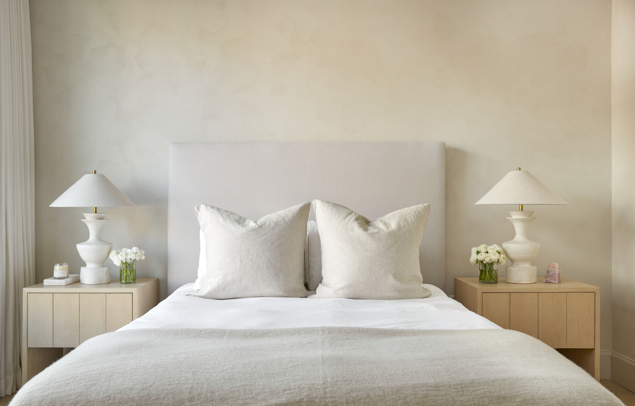 minimalist bedroom with light pink walls and light wood bedside tables, white lamps
