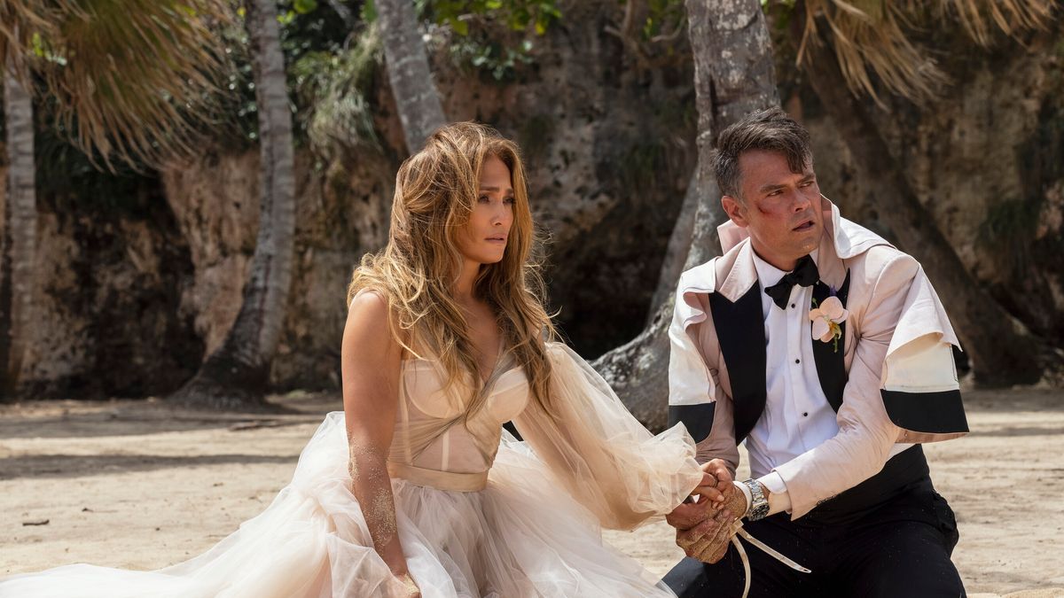 Jennifer Lopez and Shotgun Wedding stars Jennifer Lopez and Josh Duhamel on a beach in wedding clothes for Shotgun Wedding