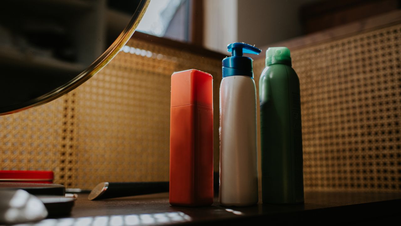 Selection of three skincare products on a dressing table next to a small mirror