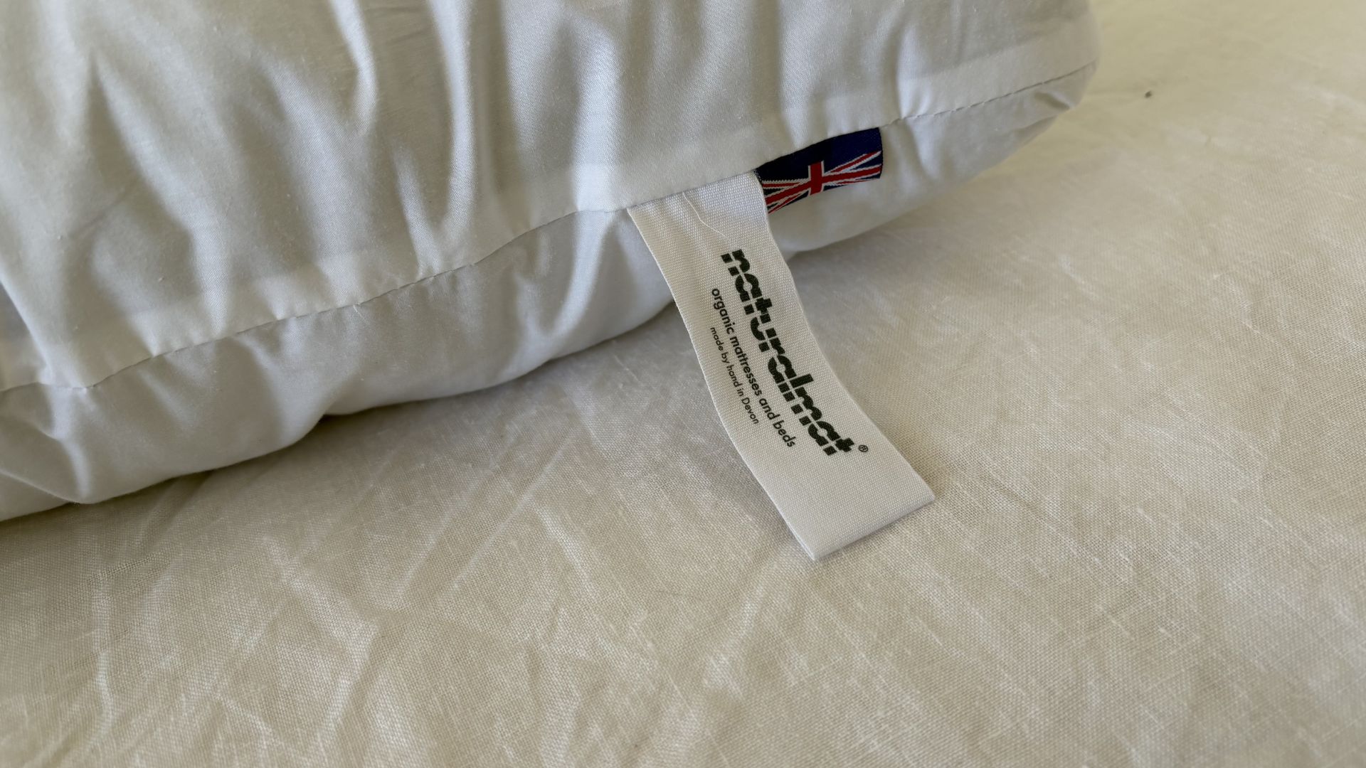 The Naturalmat The Centre Stitched Wool Pillow on a bed