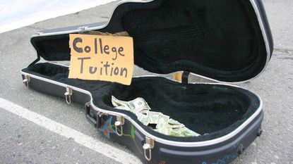 A guitar case on a street open with some money in it and a hand-written sign that reads "College Tuition."