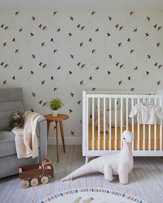 baby's nursery with white crib bird wallpaper dinosaur toy
