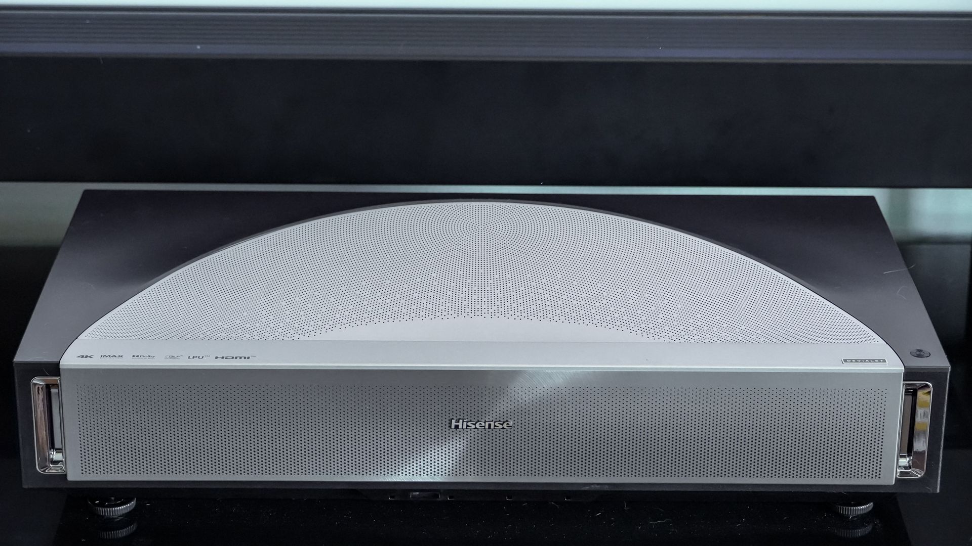 A Hisense PX4 Pro projector on a home media center shelf