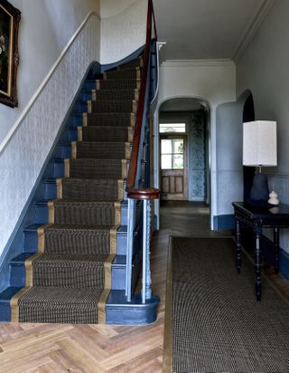 Hallway with staircase painted in blue with a runner and white walls