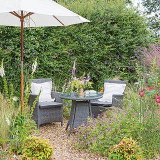 A shaded seating area with grey outdoor furniture set and cream coloured parasol umbrella