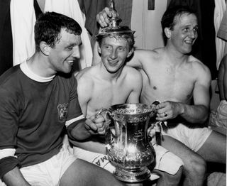 Teammate Maurice Setters places the lid of the FA Cup on Denis Law's head after Manchester United's victory over Leicester in the 1963 final