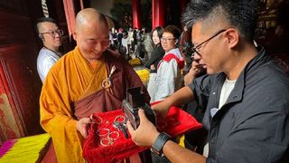 A Buddhist monk blesses a Hasselblad film camera at the Shaolin Temple in Henan, China