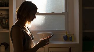 Silhouette of a woman holding and texting on phone in the bathroom, phubbing at home