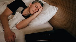 Man lying in bed unable to sleep