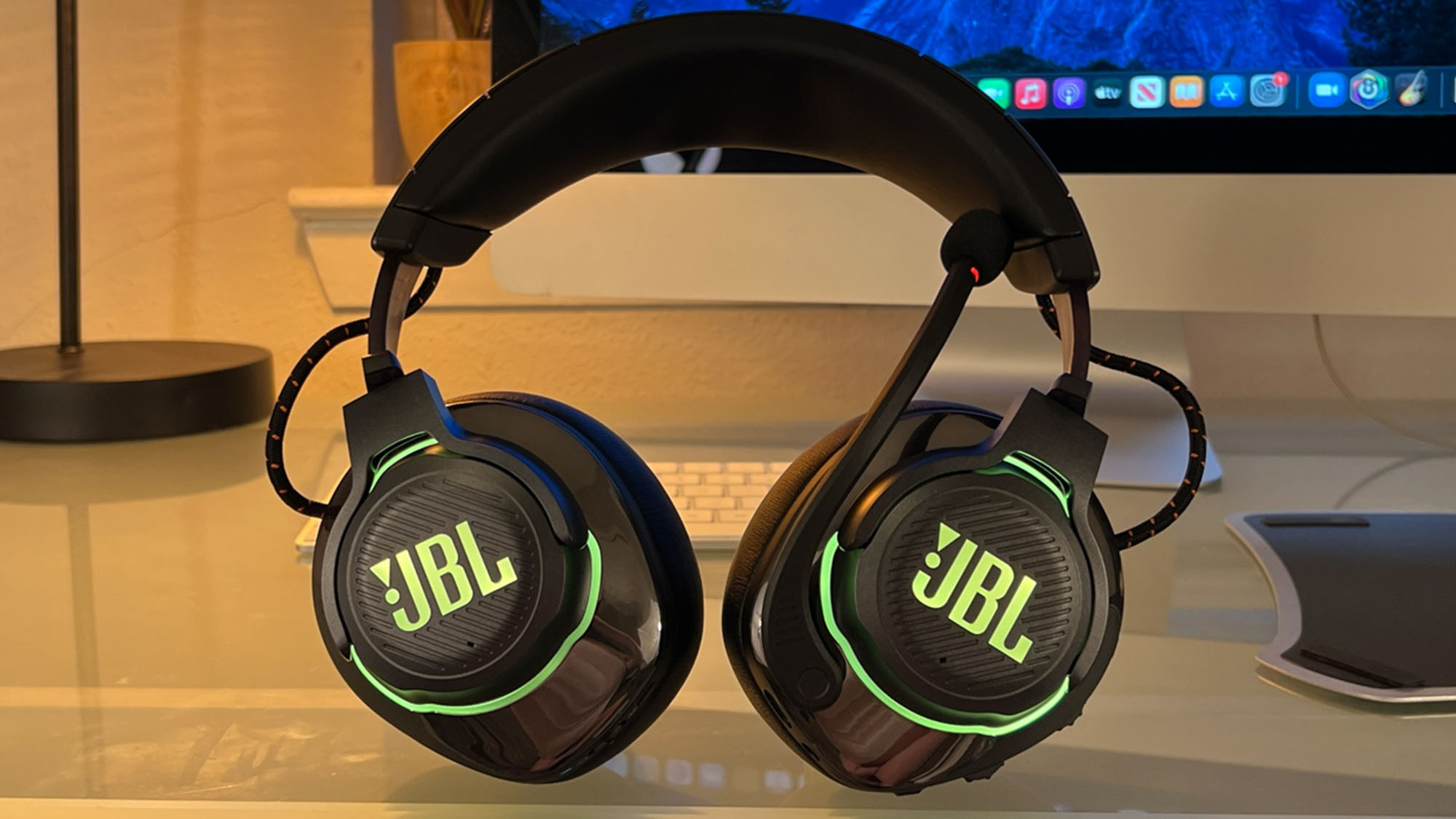 Et headset av typen JBL Quantum 810 Wireless på et skrivebord.