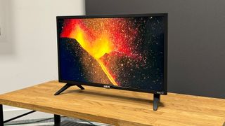 RCA Roku TV 24-inch (RK24HF1) small TV slight angle on wooden TV bench showing volcanic eruption on screen