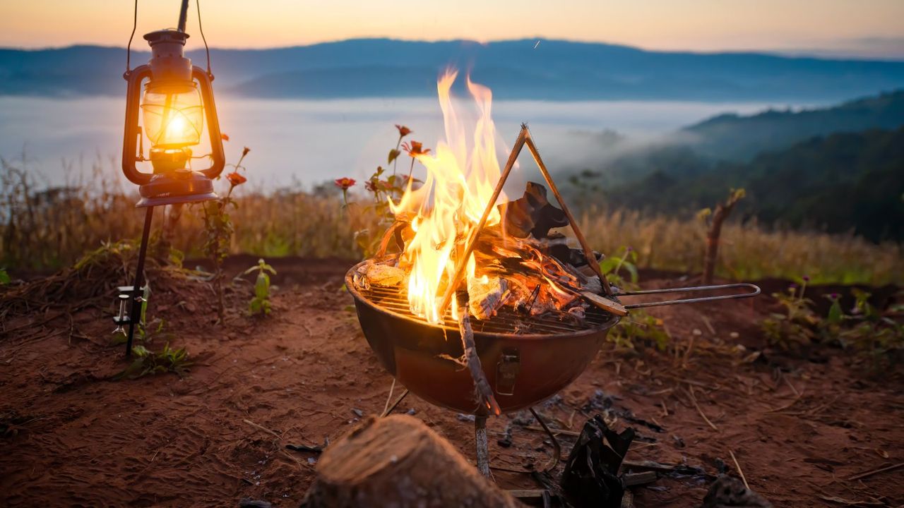 A portable grill on a hillside in front of a sunrise