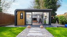 A garden path with pavers and shingle leading up to a garden room studio 