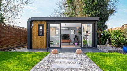 A garden path with pavers and shingle leading up to a garden room studio